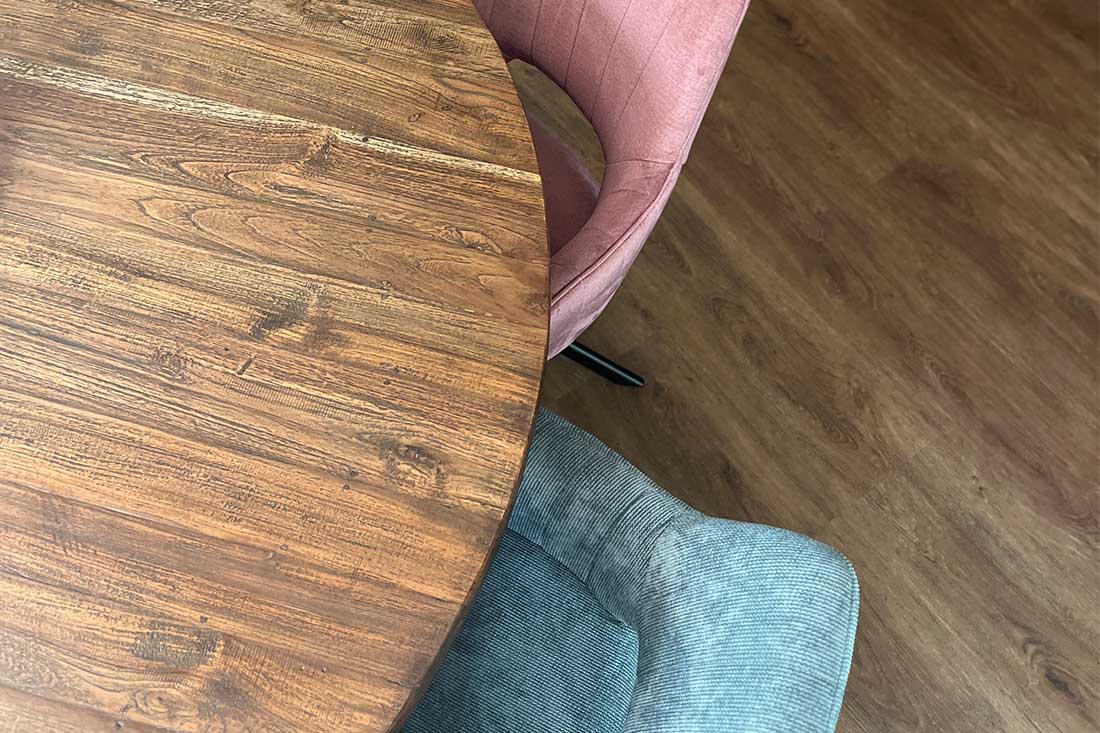 Ronde houten eettafel met roze en grijze eetkamerstoel met open rugleuning