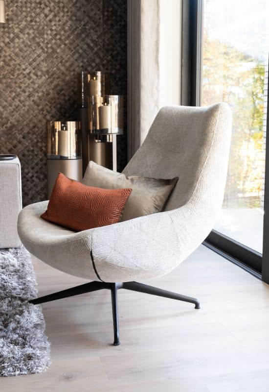 fauteuil cremekleurig met sierkussens in woonkamer