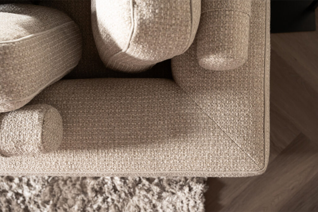 Beige stoffen hoekbank rolletjes rugkussen