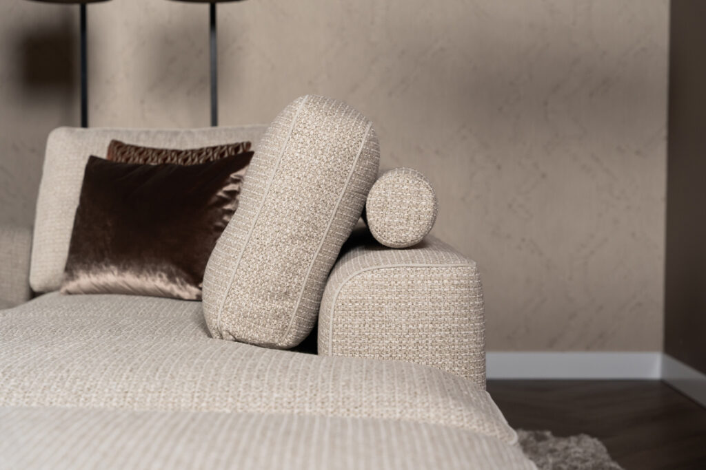 Stoffen hoekbank beige rolletjes achter rugkussen